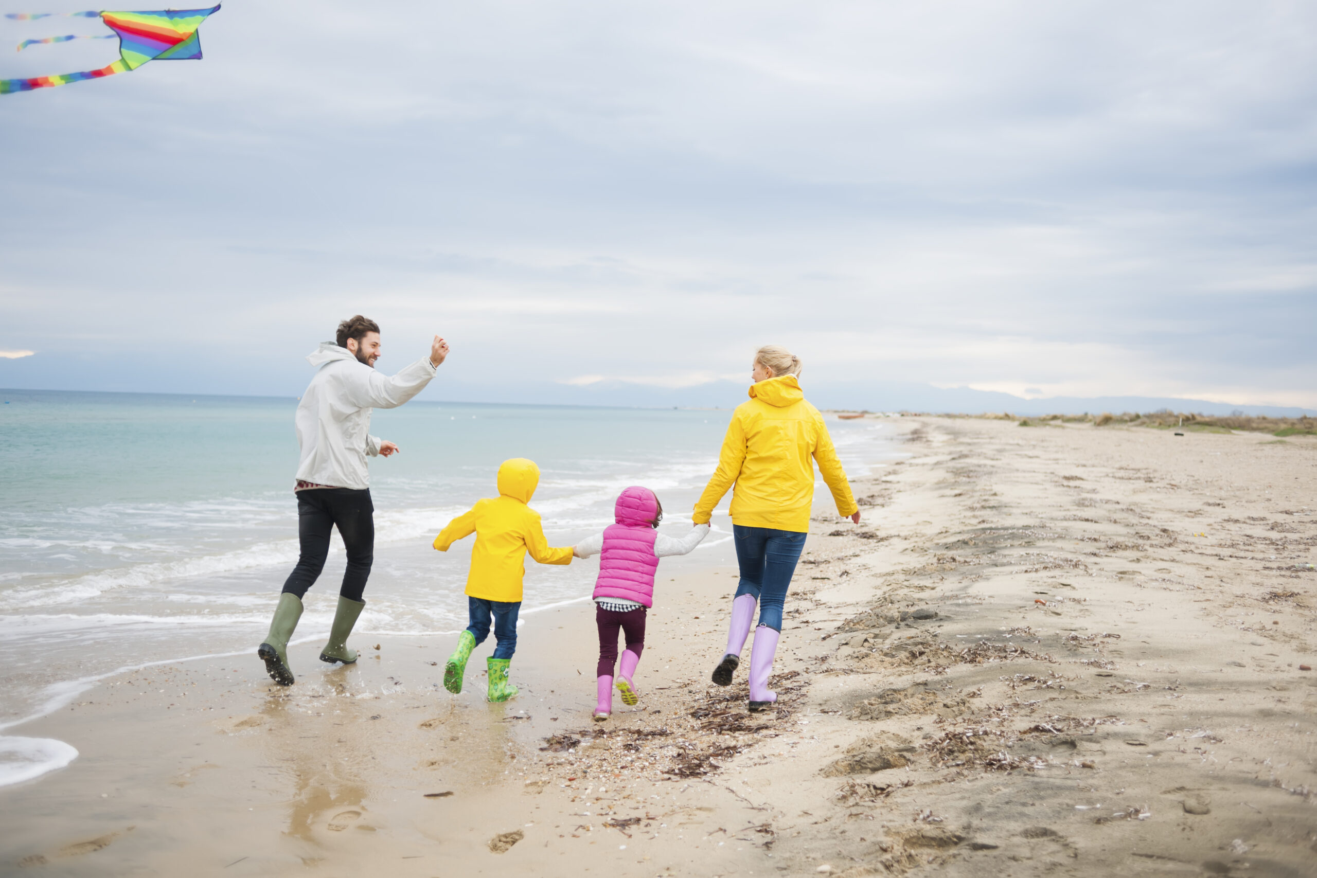 Young Family Flying Kite On Beach